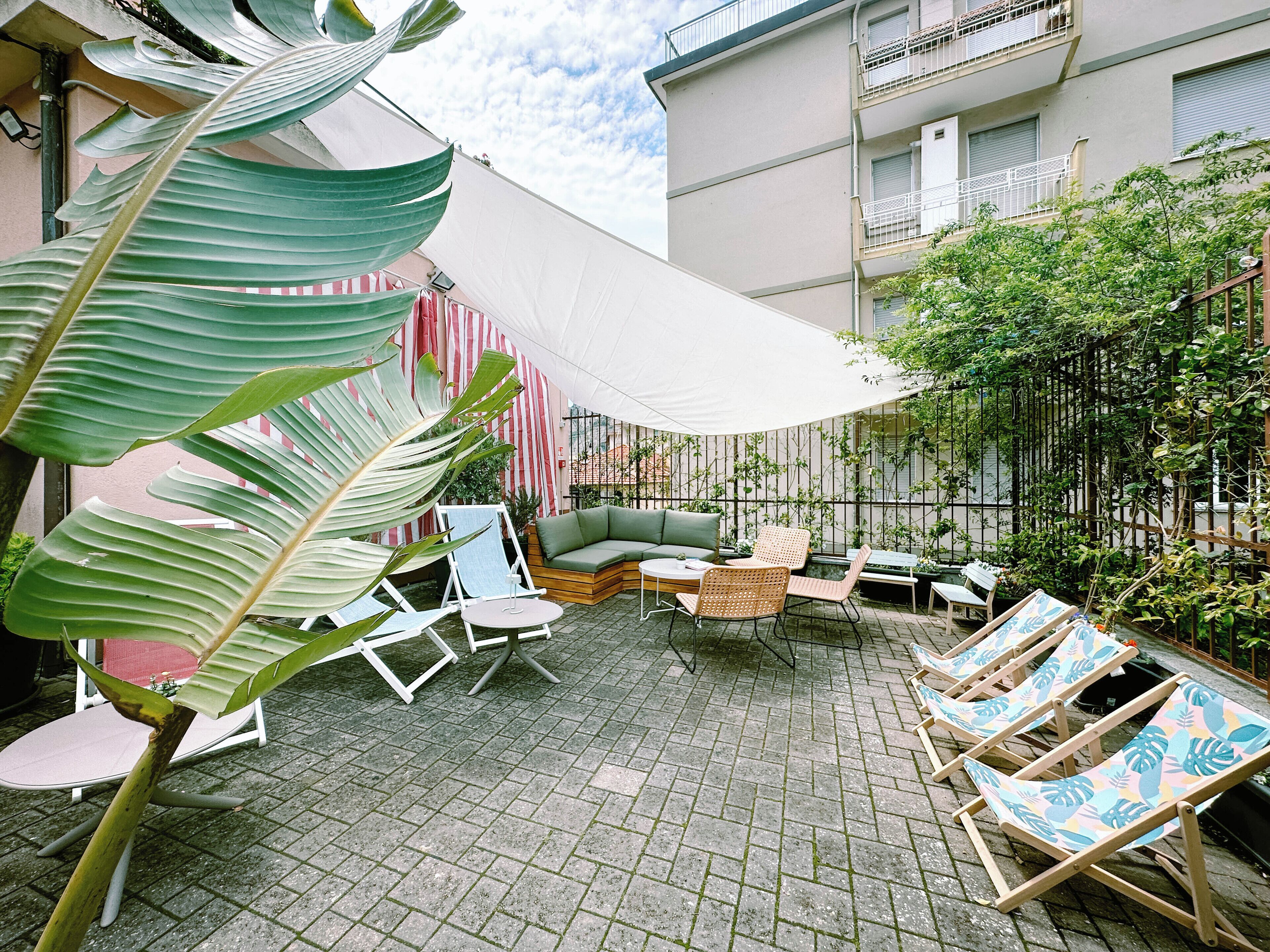 Ein möblierter Außenbereich mit einer Sitzecke, inklusive einer Couch, Stühlen und einem Tisch.