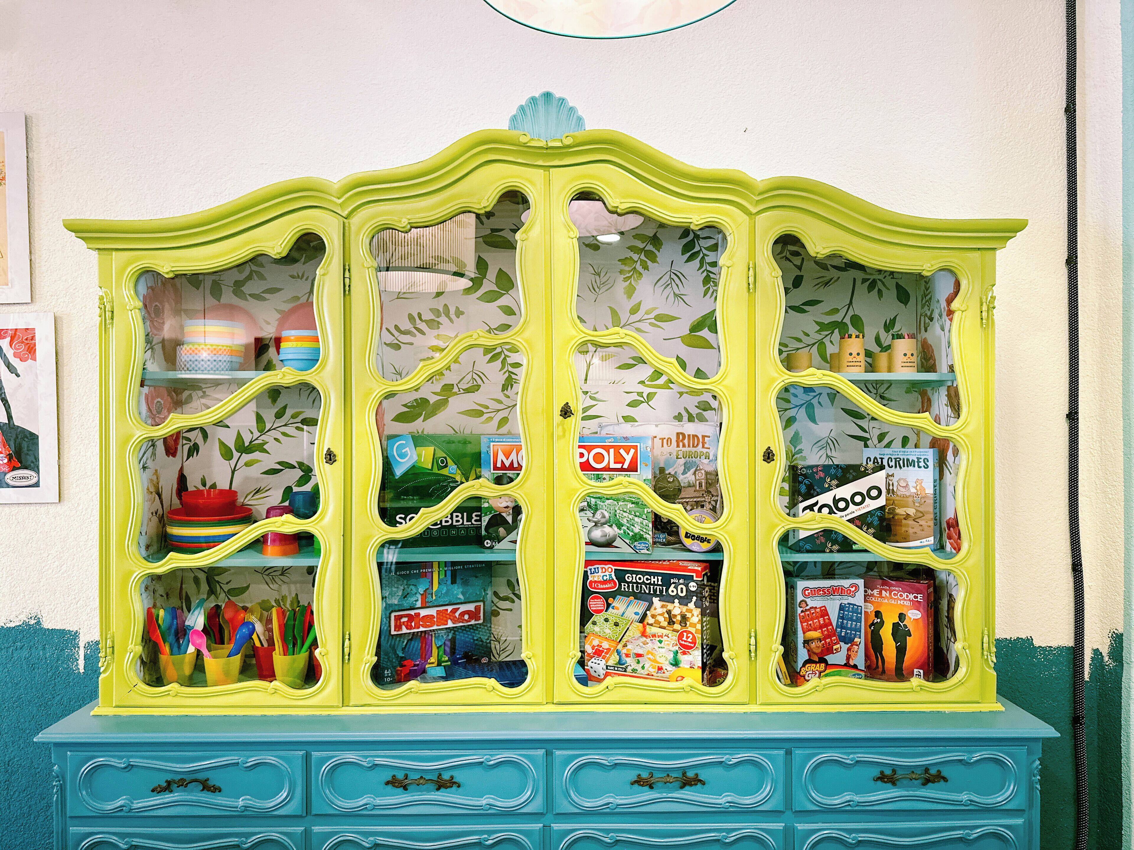 A brightly colored cabinet with multiple compartments, each containing various board games and toys.