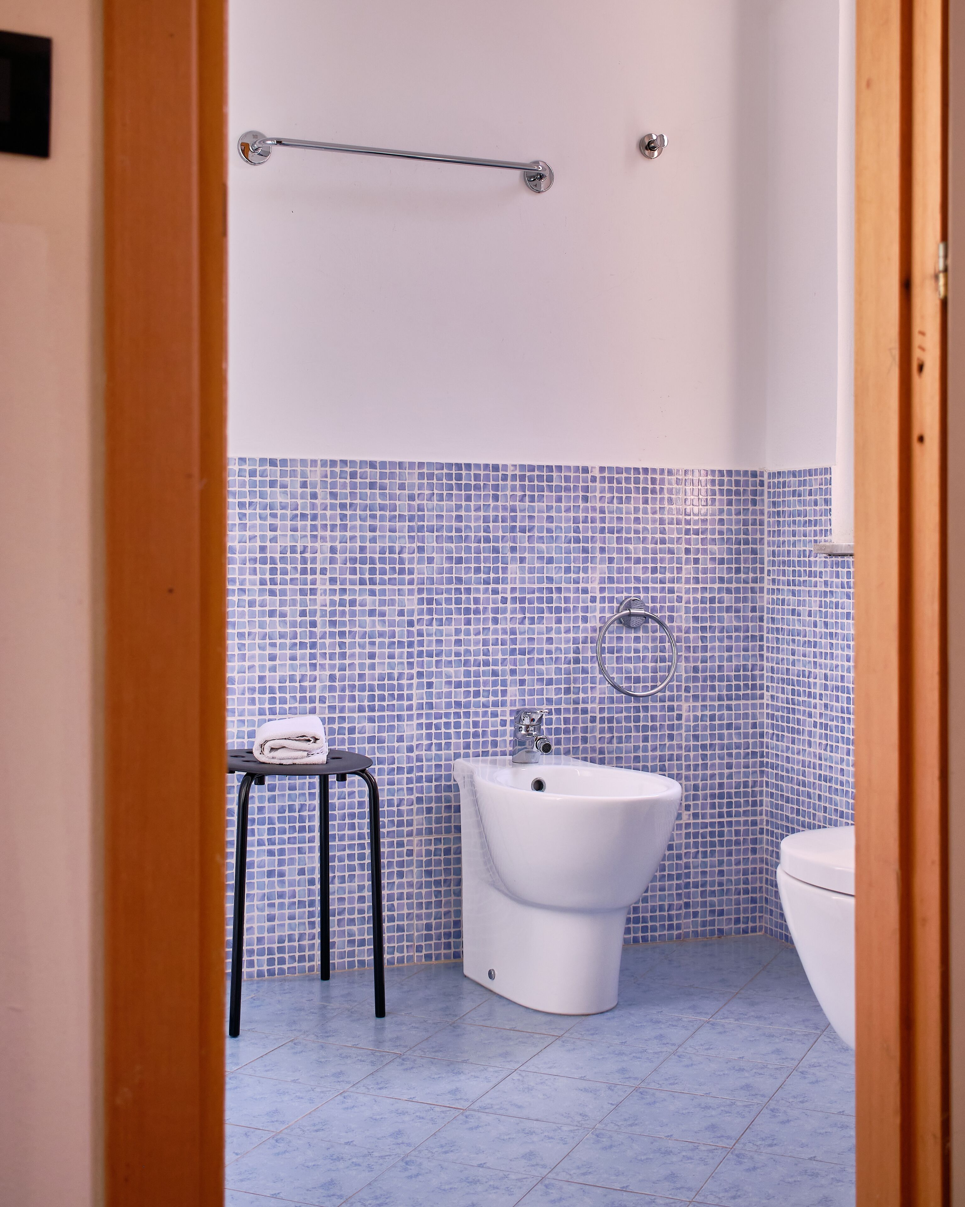 A bathroom with a white sink, a bidet, and a small table with a towel.