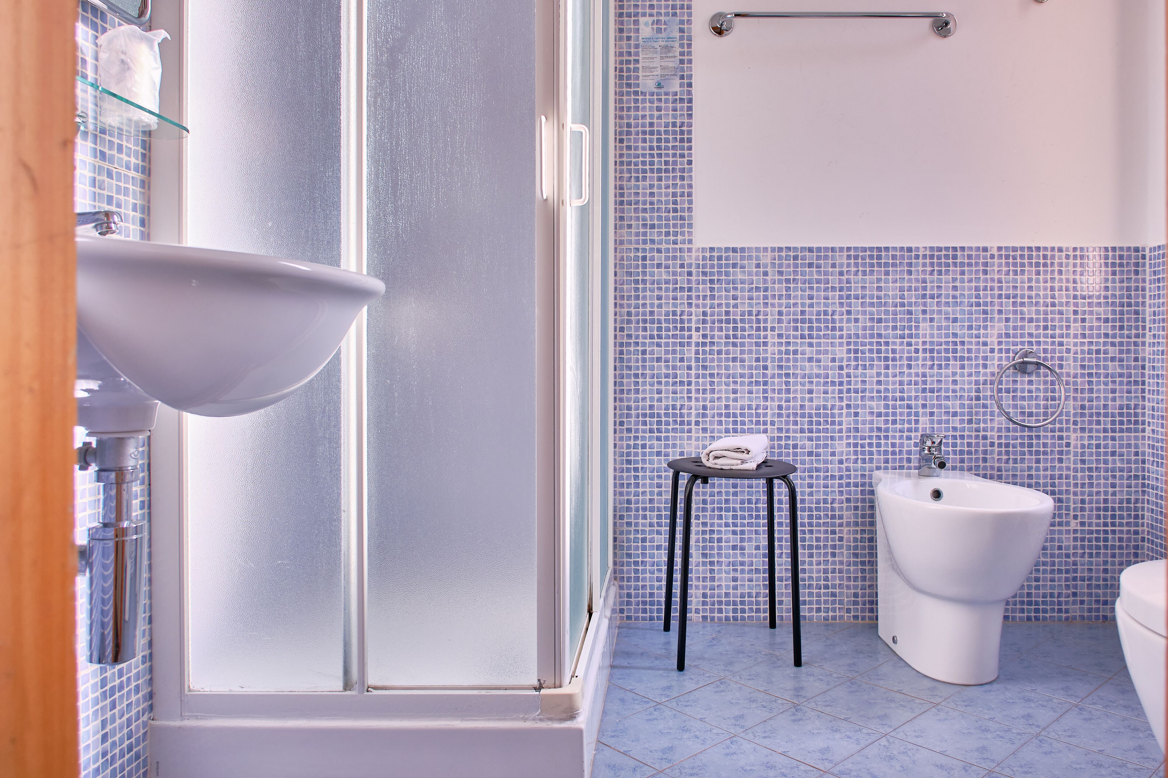 A bathroom with a white sink, a bidet, and a small stool.