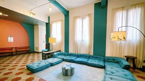 Una habitación con sofá modular, alfombra estampada, banco y lámpara.