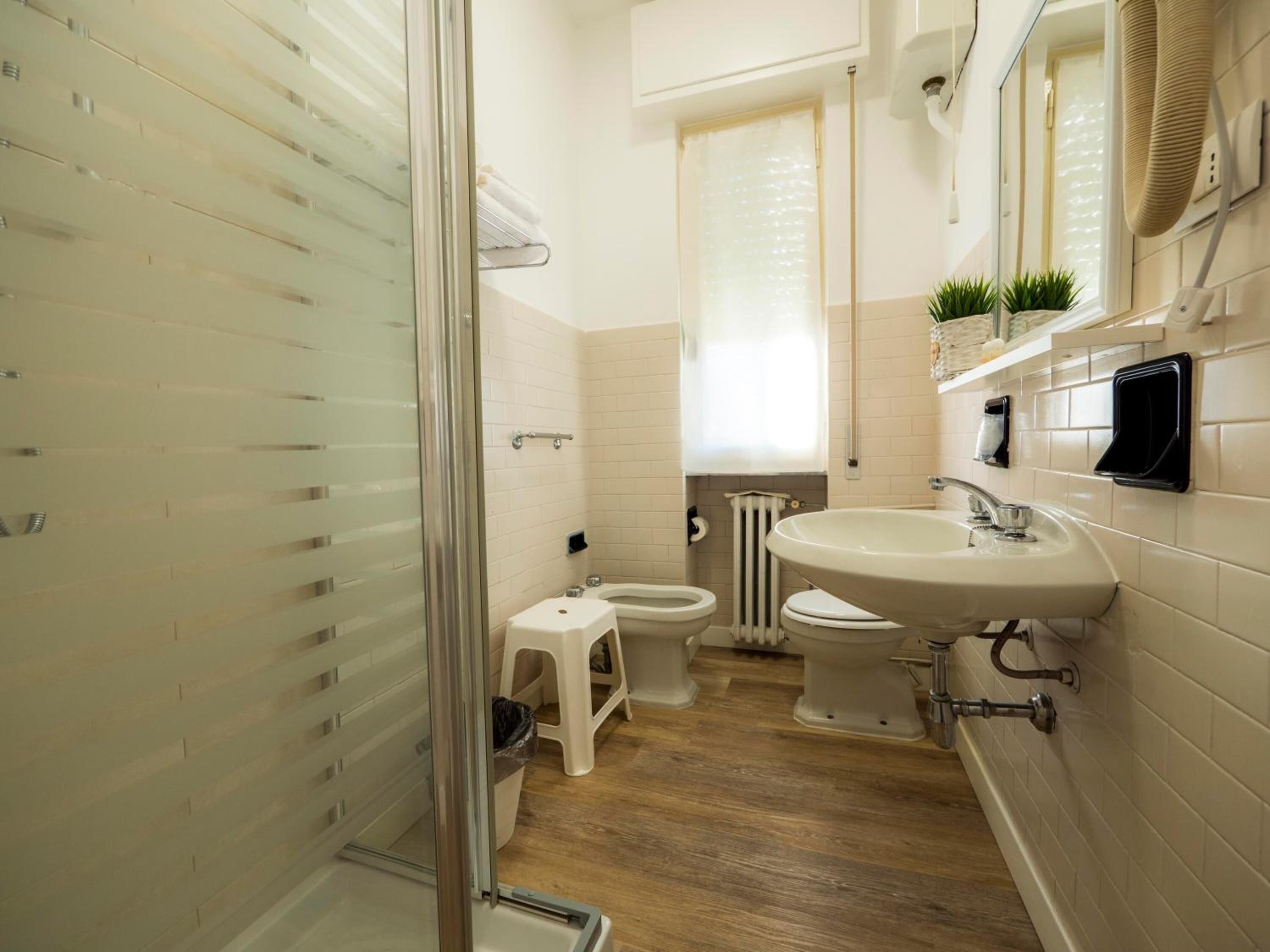 Ein Badezimmer mit Duschkabine, Waschbecken, Toilette und Handtuchheizkörper.
