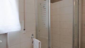 A bathroom with a glass-enclosed shower, a white sink, and a towel rack.