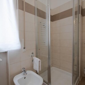 A bathroom with a glass-enclosed shower, a white sink, and a towel rack. - Continental (Pietra Ligure)