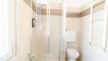 Un bagno con doccia vetrata, un water e un portasciugamani.