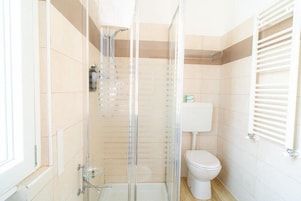 Un baño con ducha de vidrio, inodoro y perchero para toallas.