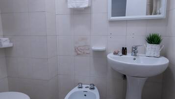 A bathroom with a toilet, bidet, and sink.