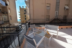 A balcony with a table, chairs, and a small decorative item.
