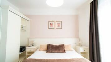 A hotel room with a bed, bedside tables, a wardrobe, and a ceiling light.