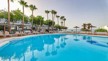 A swimming pool with lounge chairs and palm trees.