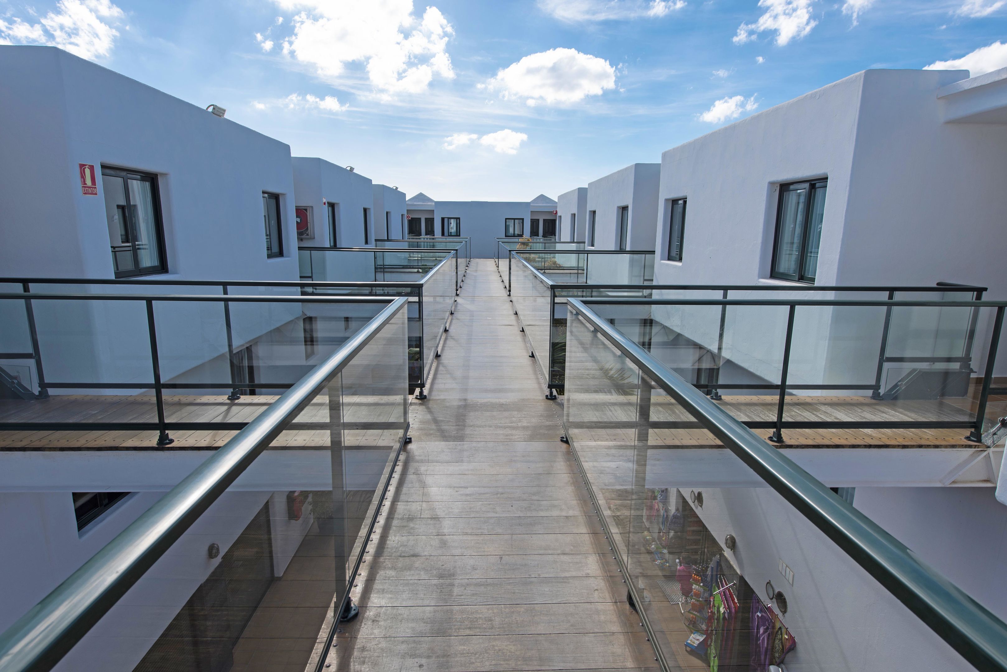 Een moderne hotelgang met glazen balustrades en een centrale doorgang.