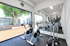 A gym with exercise bikes, a mirrored wall, and a view of the outside. - THB Flora Aparthotel (Tías)