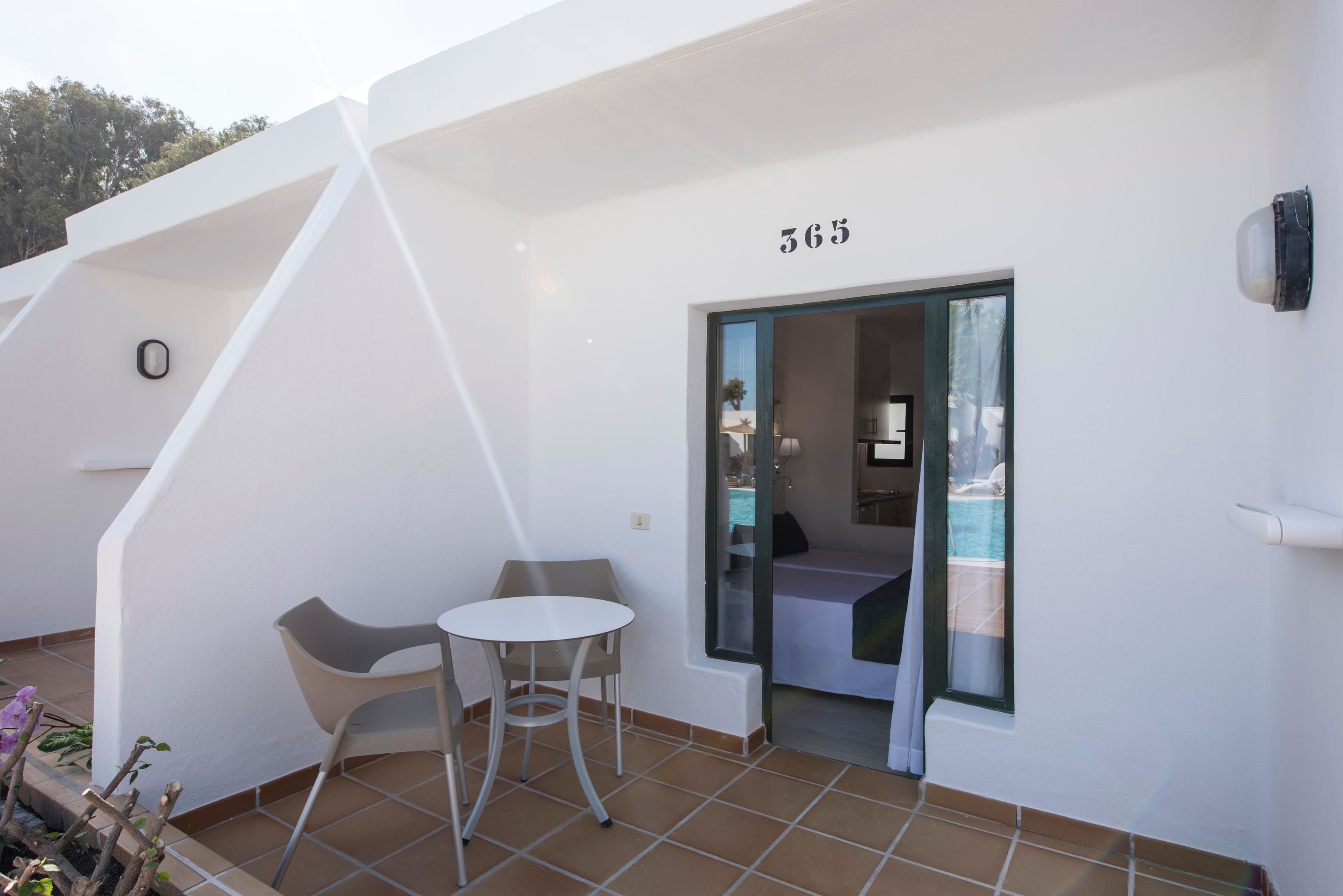 A modern hotel room with a balcony, a small table, and a chair.