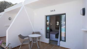 A modern hotel room with a balcony, a small table, and a chair.