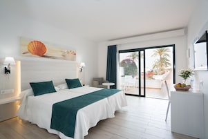 A hotel room with a large bed, a view of the outdoors, a desk, and a chair.
