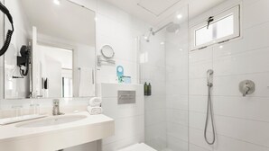 Moderni kylpyhuone, jossa on valkoinen pesuallas, peili ja wc-istuin.