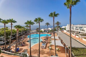 Un resort con una piscina grande, palmeras y vista al mar.