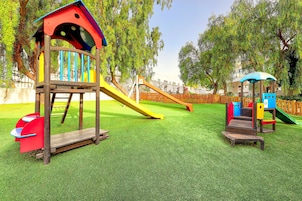 Un parque infantil con una estructura de madera para escalar y un tobogán.