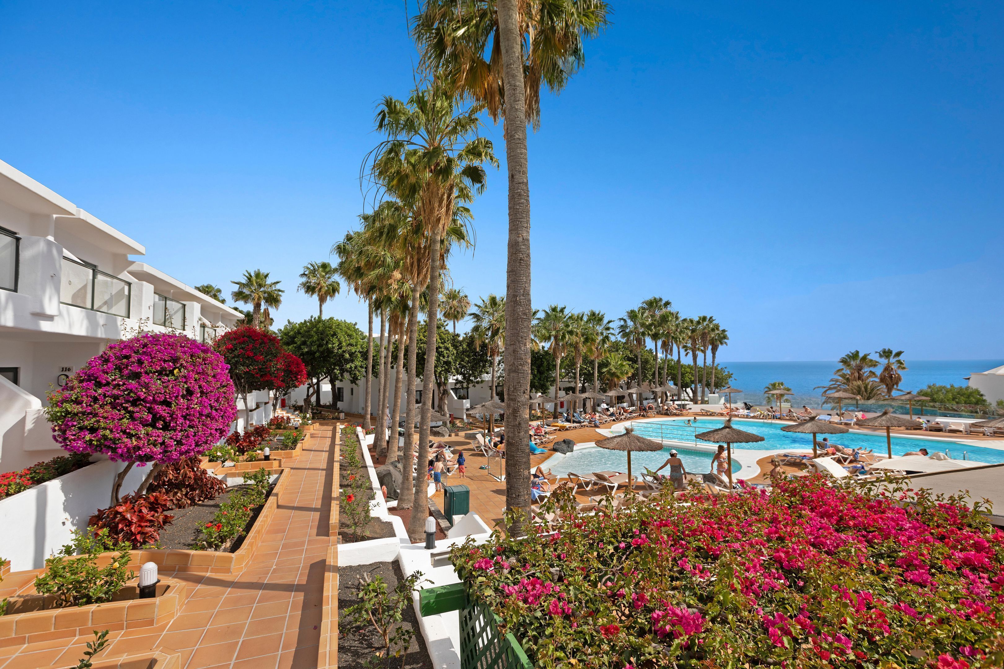 Un resort con piscina, palmeras y un cielo azul despejado.