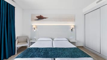 Una habitación de hotel con una cama, dos mesitas de noche, una silla, un ventanal grande y una obra de arte colgada en la pared.