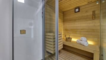 A sauna with wooden walls and a bench, a clock, and towels on the bench.