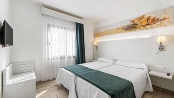 Ein Hotelzimmer mit Bett, Fernseher, Schreibtisch und einem Fenster mit Vorhängen.