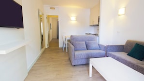A modern living room with a grey sofa, a white coffee table, and a flat-screen TV mounted on the wall. - THB Flora Aparthotel (Tías)