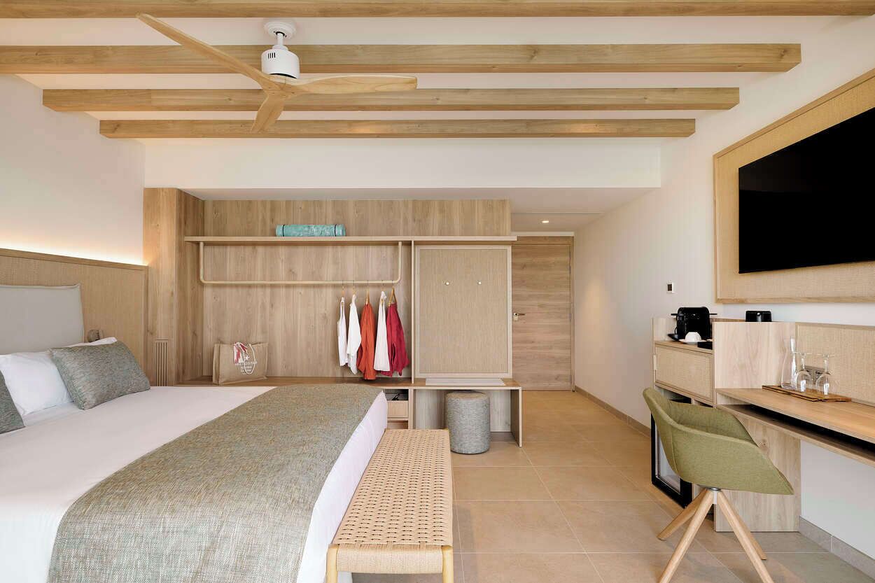 Una habitación de hotel moderna con una cama grande, un escritorio, un armario y un televisor.