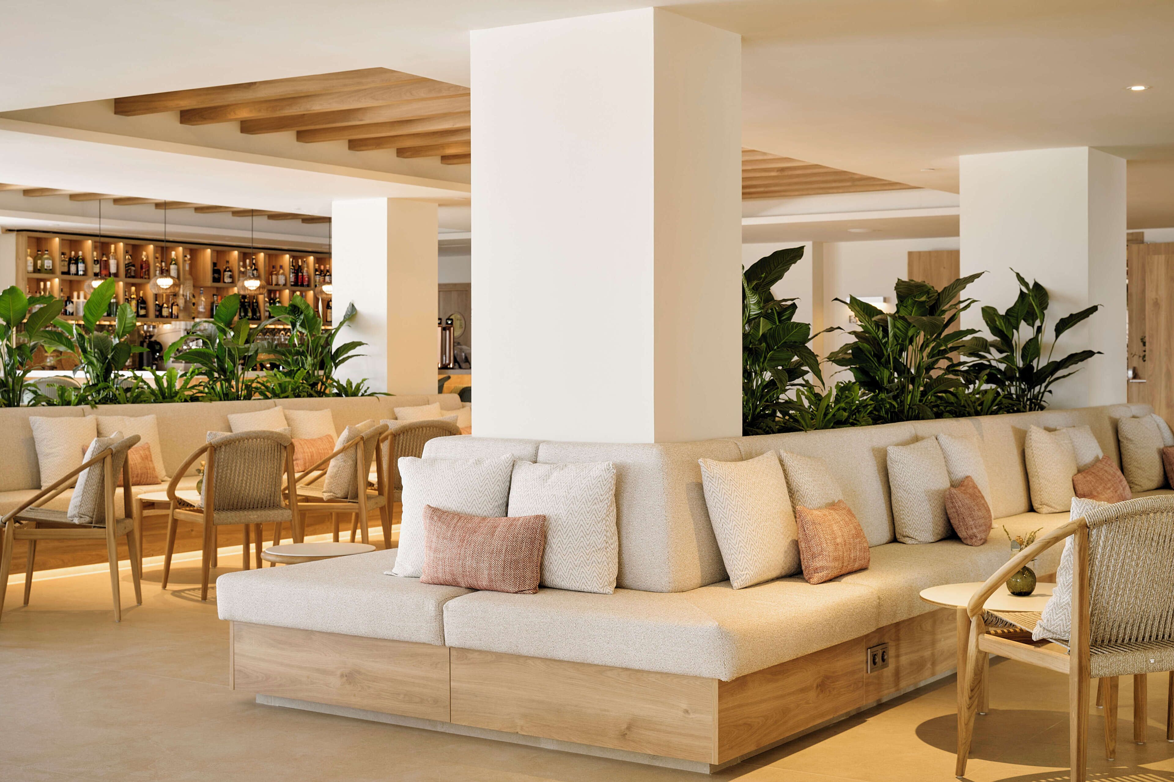 Un área de lounge moderna con un sofá, sillones y una barra al fondo.