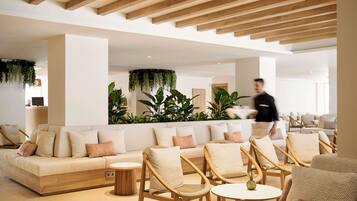 A modern lounge area with a sofa, wicker chairs, and a round table.