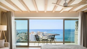 A bedroom with a large window, a bed, a bedside table, and a chair. - Iberostar Selection Es Trenc (Ses Salines)