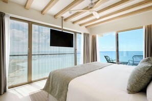 A hotel room with a large bed, a ceiling fan, a flat-screen TV, and a balcony with a view of the sea. - Iberostar Selection Es Trenc (Ses Salines)