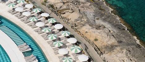 An aerial view of a resort with a pool, sun loungers, and umbrellas.