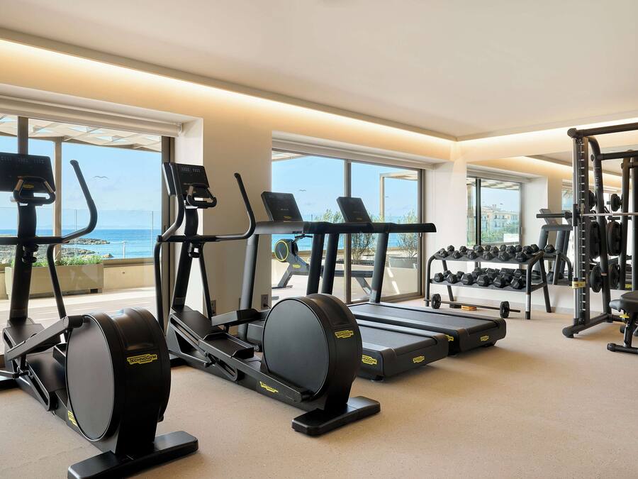 Un gimnasio con máquinas de cardio, equipo de levantamiento de pesas y mancuernas.
