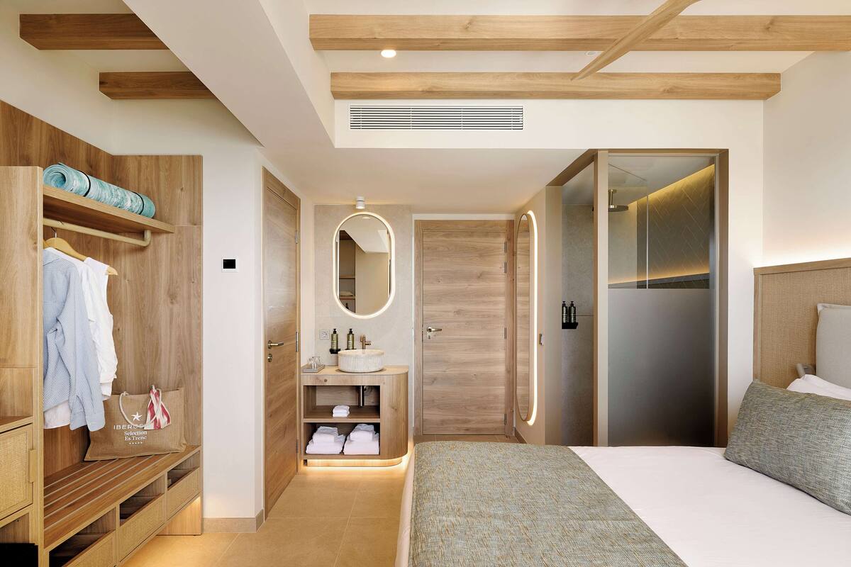Une chambre à coucher moderne avec une armoire en bois, une coiffeuse avec un miroir et un lit doté d’une tête de lit grise.