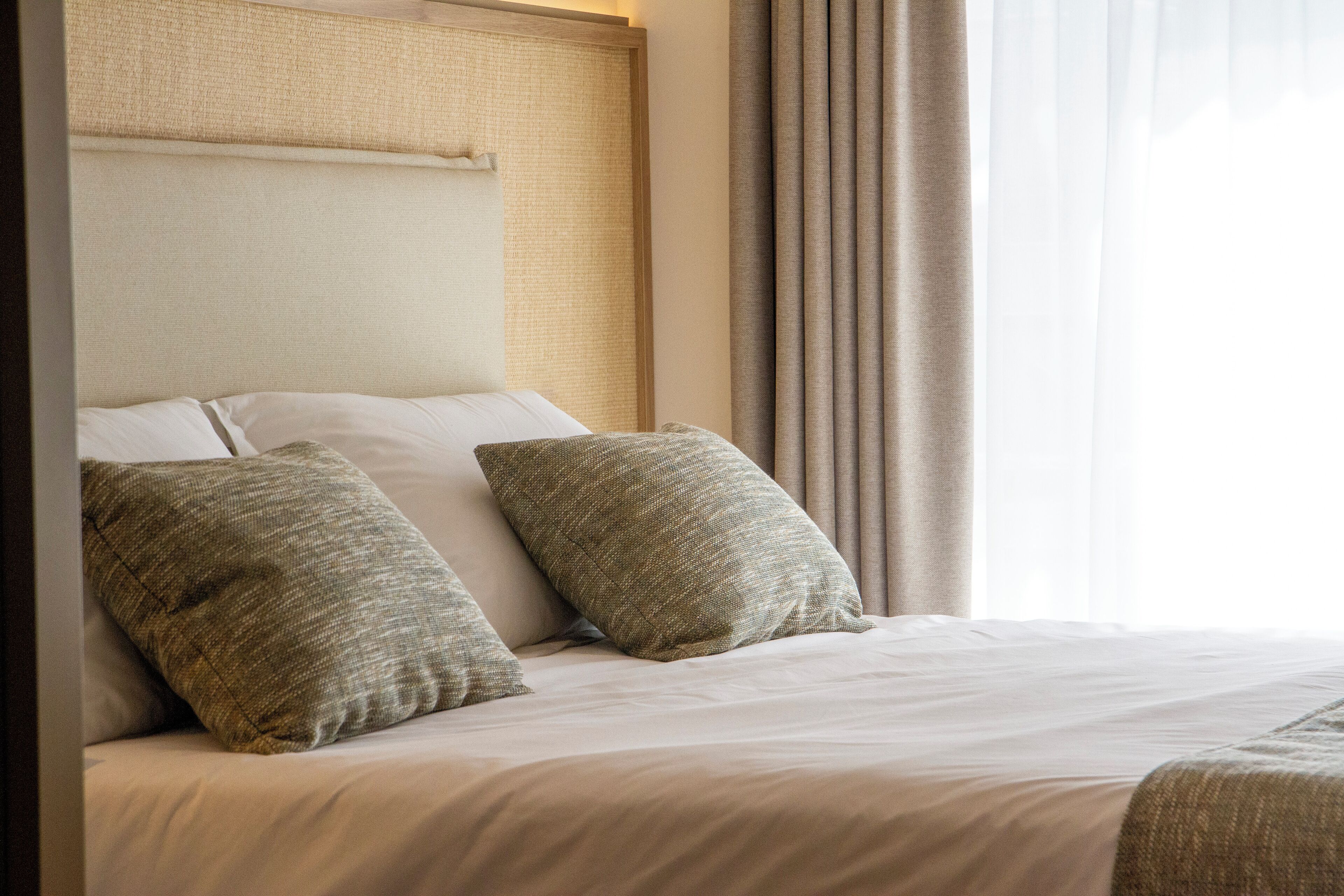 A neatly made bed with two pillows and a headboard with a textured panel.