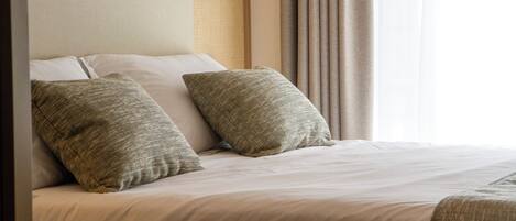 A neatly made bed with two pillows and a headboard with a textured panel.