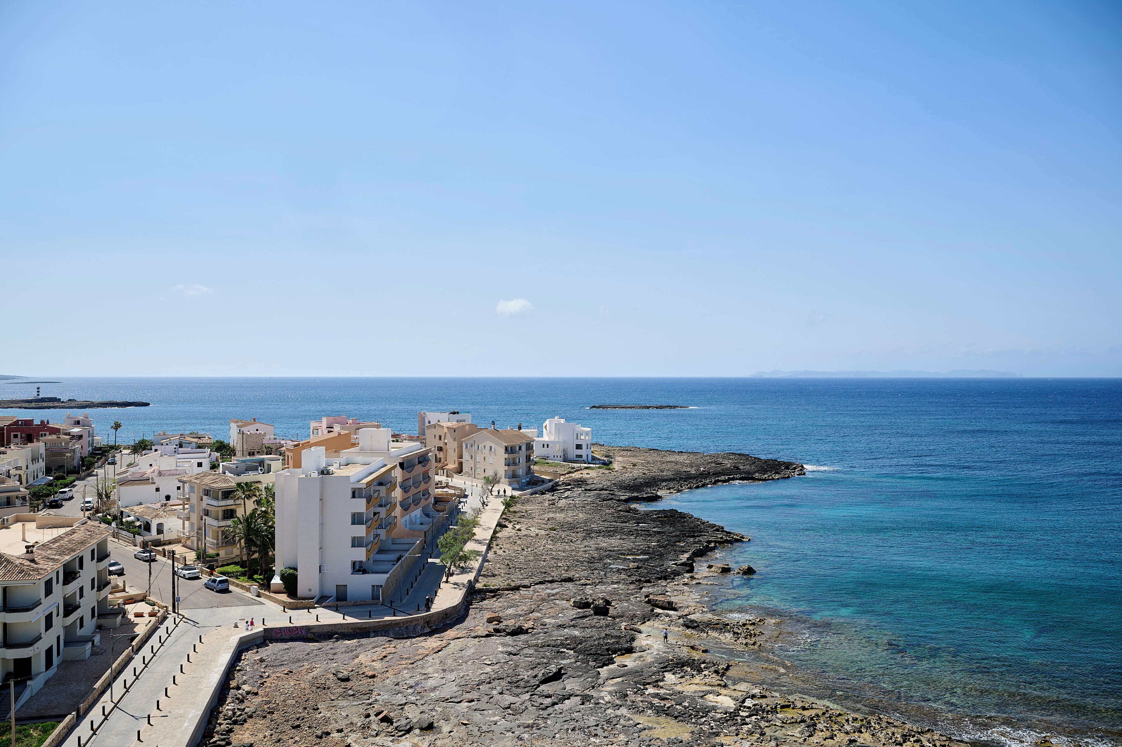 Une ville côtière avec des bâtiments qui bordent la plage, une plage rocheuse et la mer.