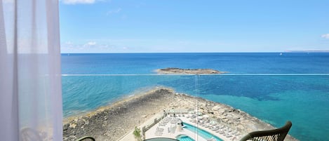 Un balcón con vista a la playa y a una piscina.