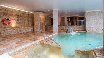 Una gran piscina cubierta con un elemento acuático transparente, paredes alicatadas y un flotador en la pared.