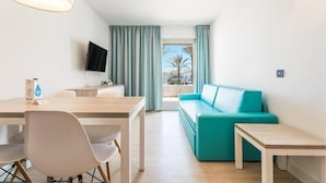 A modern hotel room with a dining area, a sofa, and a TV. - Aparthotel THB Guya Playa (Capdepera)