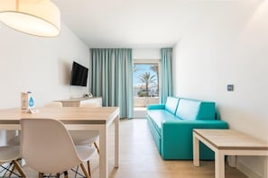 Una habitación de hotel moderna con comedor, sofá y televisor.