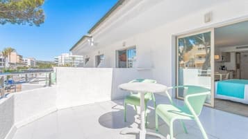 Un patio moderno al aire libre con una mesa y sillas, un ventanal corredero que da a una habitación, y vistas del entorno.