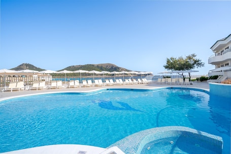 Una piscina techada, una piscina al aire libre, sombrillas