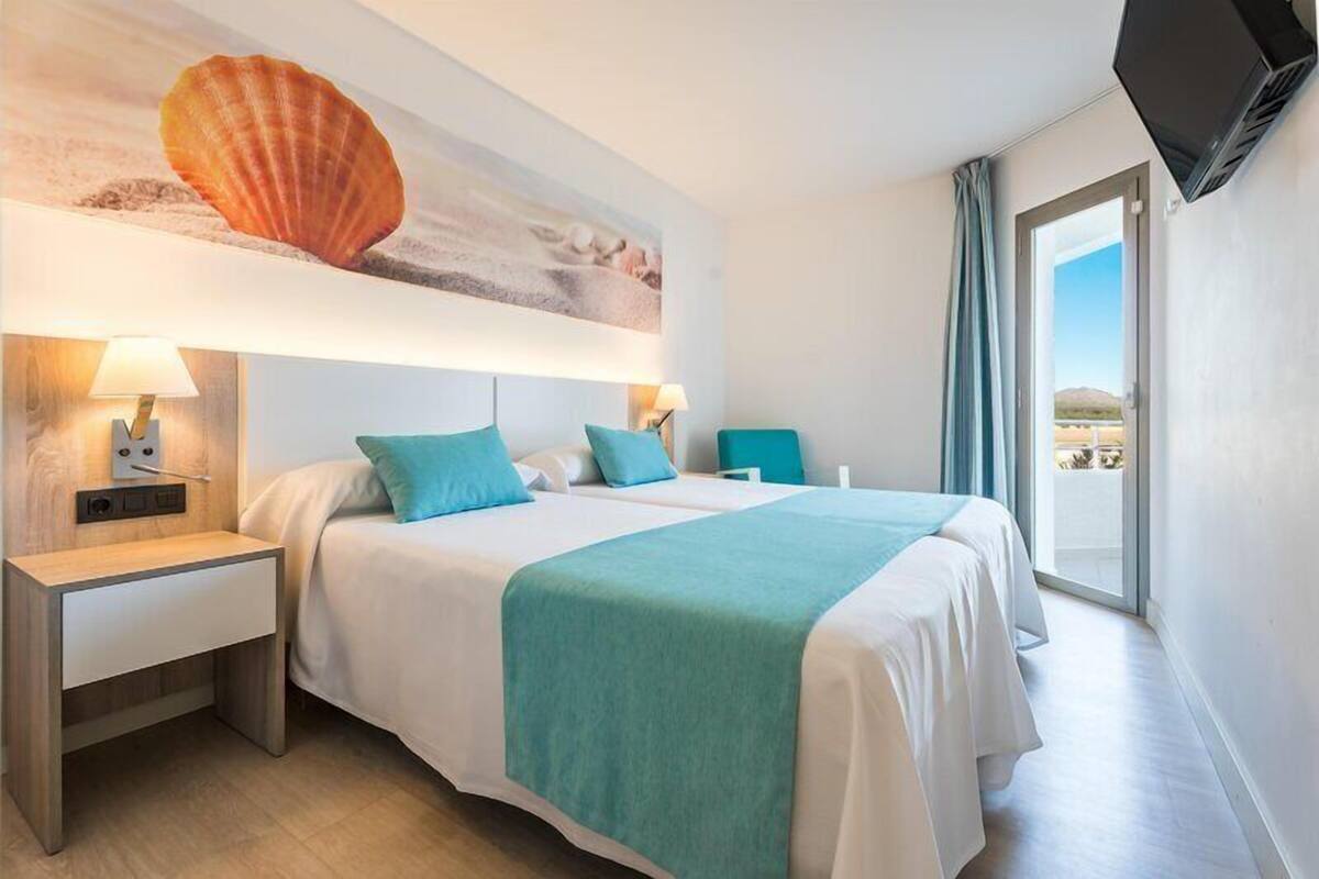 A hotel room with a bed, two bedside tables, a TV, and a large window with a view.