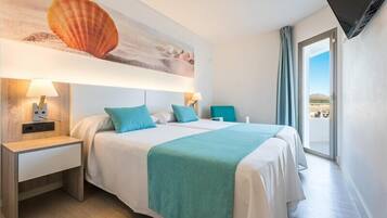 Habitación de hotel con cama, dos mesitas de noche, televisor y un amplio ventanal con vistas.