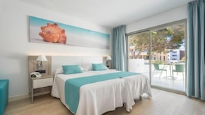 A hotel room with a bed, a nightstand, a lamp, a large window with curtains, and a view of the outside. - Aparthotel THB Guya Playa (Capdepera)