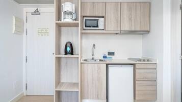 A compact kitchenette with a microwave, coffee maker, and a small refrigerator.