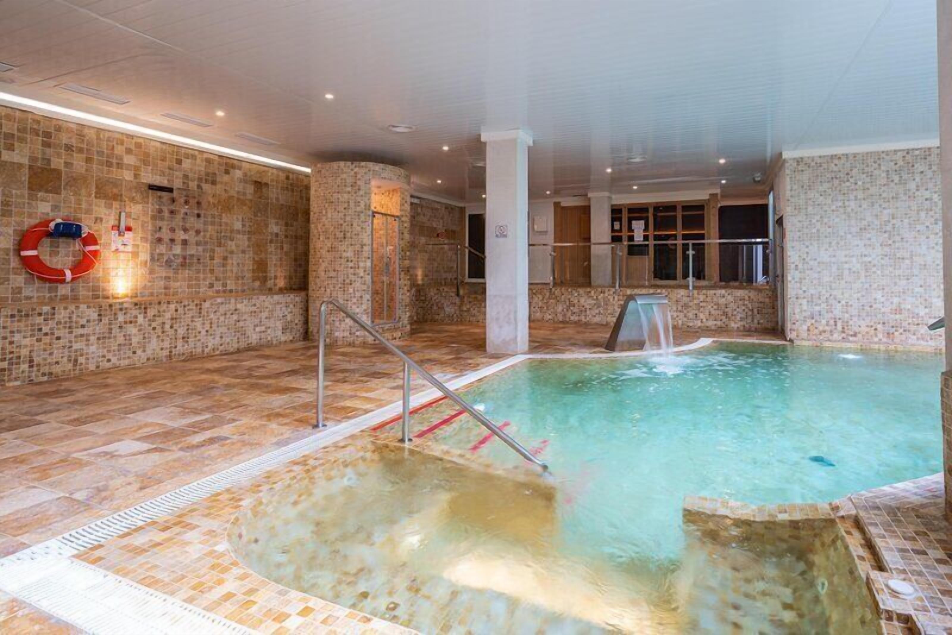 Una piscina cubierta, una piscina al aire libre, sombrillas, tumbonas