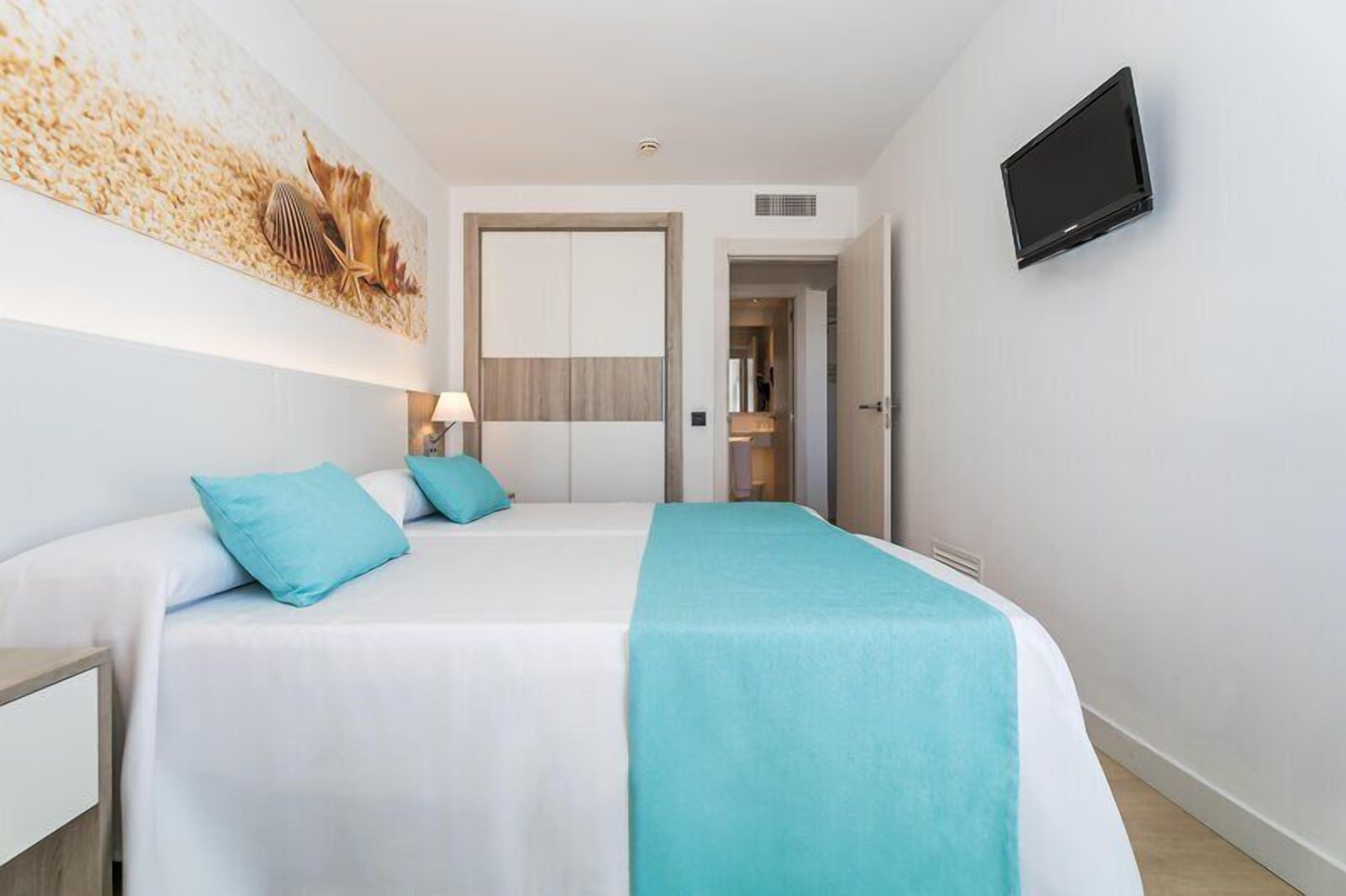 A hotel room with a bed, a TV, and a door leading to a bathroom.
